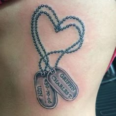 a woman's stomach with two dog tags attached to the back of her waist