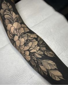 a black and white tattoo with flowers on it's arm, sitting on top of a bed