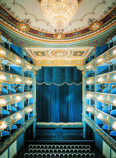 an empty theater with blue curtains and chandeliers