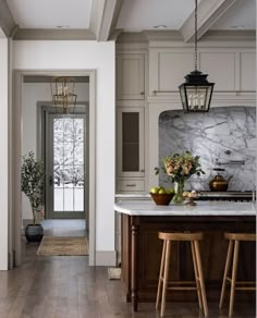 a kitchen with marble counter tops and wooden stools in front of an open door