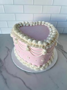 a pink and white cake sitting on top of a marble counter next to a brick wall