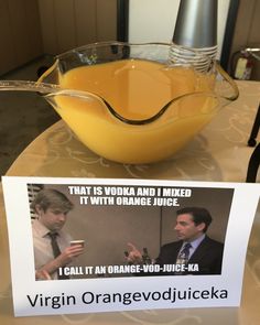 an orange juice in a glass bowl on a table next to a sign with the caption, that is vodka and i mixed it with orange juice