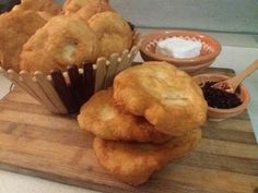 there are some muffins stacked on a cutting board with dipping sauce in the background