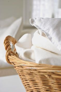 a wicker basket with white linens in it