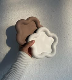 a hand holding a white and brown object in front of a white wall with snow on it