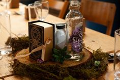 a wooden table topped with bottles and glasses filled with liquid next to an open book