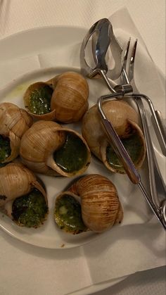 several clams on a plate with sauce and silverware