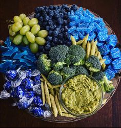 a platter with broccoli, grapes, blueberries and other food items