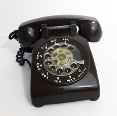 an old - fashioned telephone is sitting on a white surface and it's black