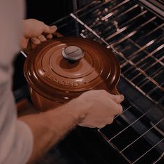 a person is opening an oven door to check on the food in the pot that's cooking