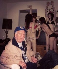 an old man sitting on a couch in front of some women