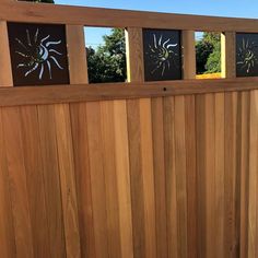 a wooden fence with metal spider decals on the top and bottom panels, in front of a blue sky