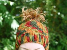 a close up of a person wearing a knitted hat with hair in the wind