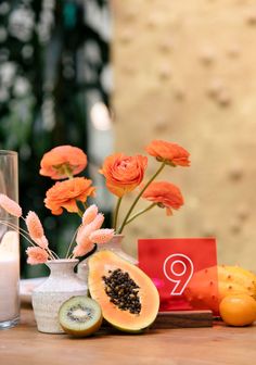 the table is decorated with orange flowers and fruit, along with a number nine sign