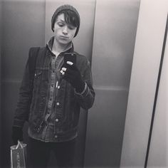 a young man standing in front of an elevator looking at his cell phone