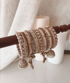 a stack of bracelets sitting on top of a table next to a white vase