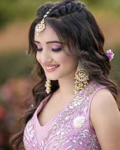 a woman in a pink dress with gold jewelry on her head and purple eyeshadow