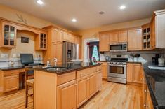 a large kitchen with wooden cabinets and black counter tops, along with stainless steel appliances