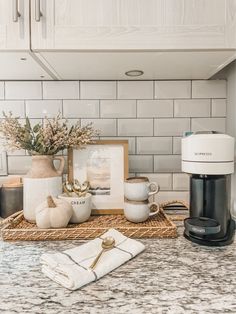 a kitchen counter with coffee maker, mugs and other items on top of it