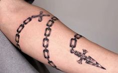 a man's arm with chains and an arrow tattoo on it