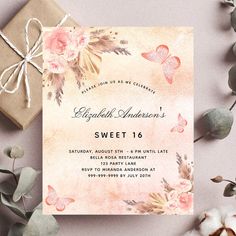 a pink and gold wedding card with flowers on it, next to a present box