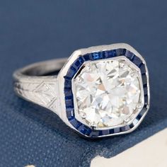 an antique diamond and sapphire ring on a blue cloth with a book in the background