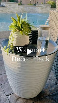 a potted plant sitting on top of a table next to a pool with water in it