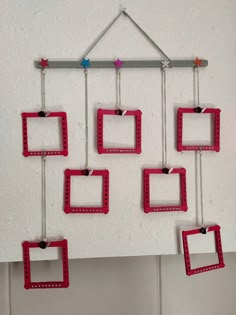 a group of square frames hanging from a wall with pegs attached to the sides