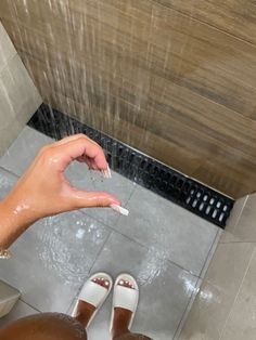 a person standing in a shower with their hand on the floor