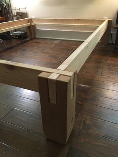 a wooden bed frame sitting on top of a hard wood floor