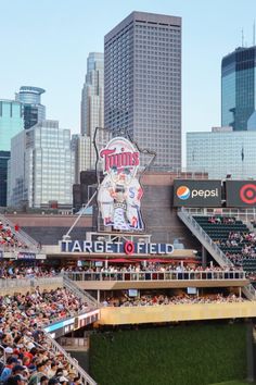 a stadium filled with lots of people sitting on the bleachers next to tall buildings