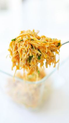 a spoon full of food sitting on top of a glass bowl filled with rice and vegetables