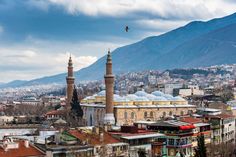 the city is surrounded by mountains and tall buildings with minarets on each side