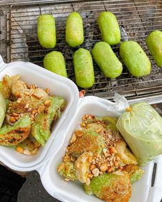 two plastic trays filled with food next to some green fruit on a bbq