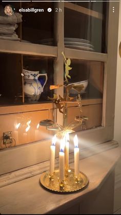 a candle holder with five lit candles in front of a window