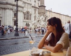 a woman sitting at a table with a glass of wine in front of her on the street