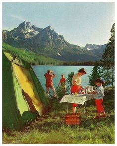 some people are camping in the mountains near a lake and a tent with food on it