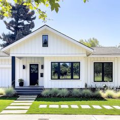 a white house with black windows and steps leading to the front door