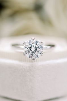 an engagement ring sits on top of a white box with a diamond in the center