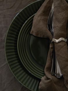 a green plate topped with a fork and knife next to a napkin on top of it