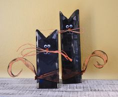 two black cats made out of toilet paper and twine with eyes drawn on them