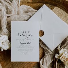 a white envelope with a gold wax stamp on it next to some flowers and fabric