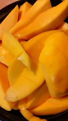 sliced mangoes in a black bowl on a table