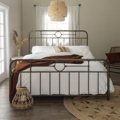 a bedroom with a metal bed frame and white linens on the pillows, brown throw pillow, and wicker basket