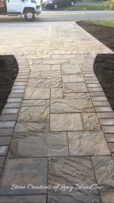 a walkway made out of pavers stone in front of a truck parked on the street