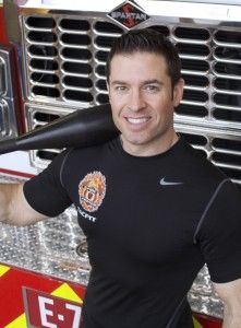 a man holding a baseball bat over his shoulder in front of a firetruck