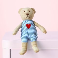 a teddy bear sitting on top of a white dresser next to a pink wall with a heart painted on it