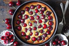 a cake with cherries on it sitting in a pan next to other desserts