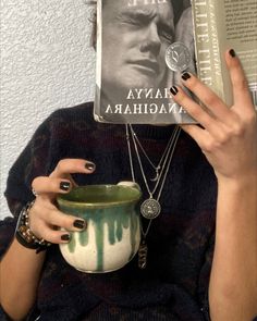 a woman holding up a book and cup