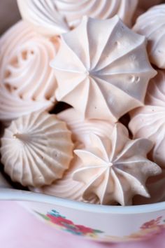 there is a bowl filled with white frosting flowers on the tablecloth, as well as other decorations